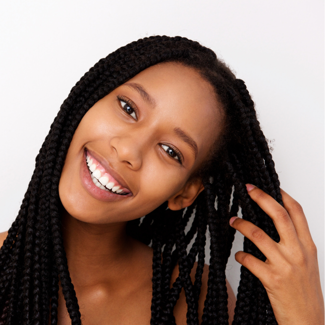 A black woman is shown carefully applying oil to her braided hair, demonstrating a nurturing and moisturizing hair care routine.