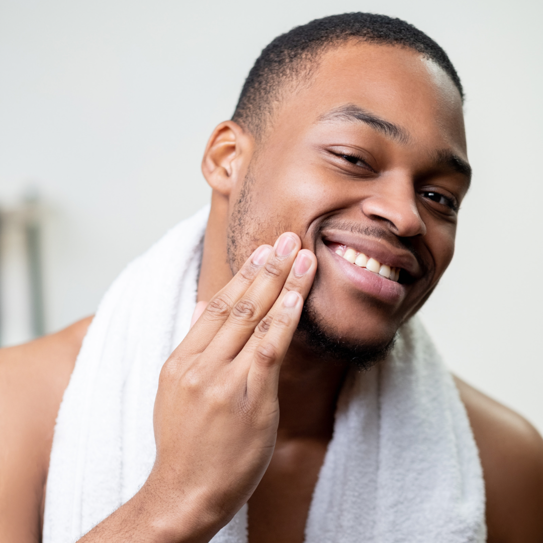 A man with his hands gently applying oil to his face, using a soothing and mindful technique.