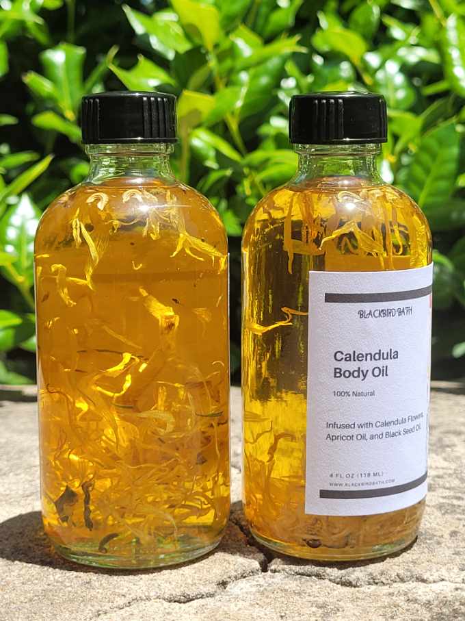 A clear glass bottle filled with Calendula Body Oil, featuring vibrant Calendula flowers suspended within, providing a visually enchanting and soothing presentation.