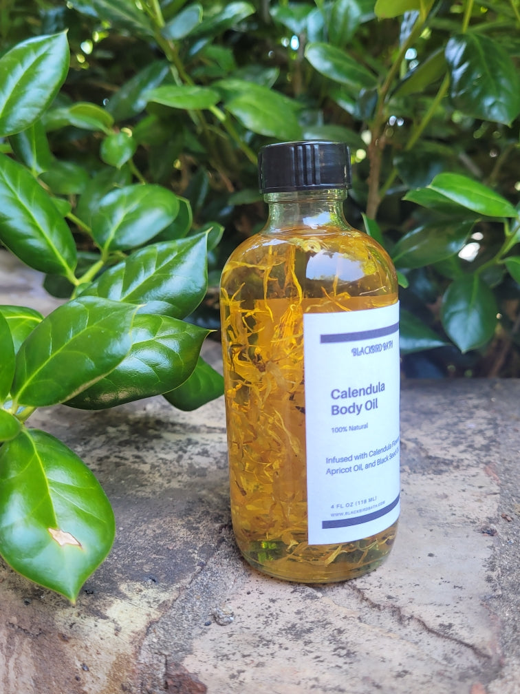 A clear glass bottle filled with Calendula Body Oil, featuring vibrant Calendula flowers suspended within, providing a visually enchanting and soothing presentation.
